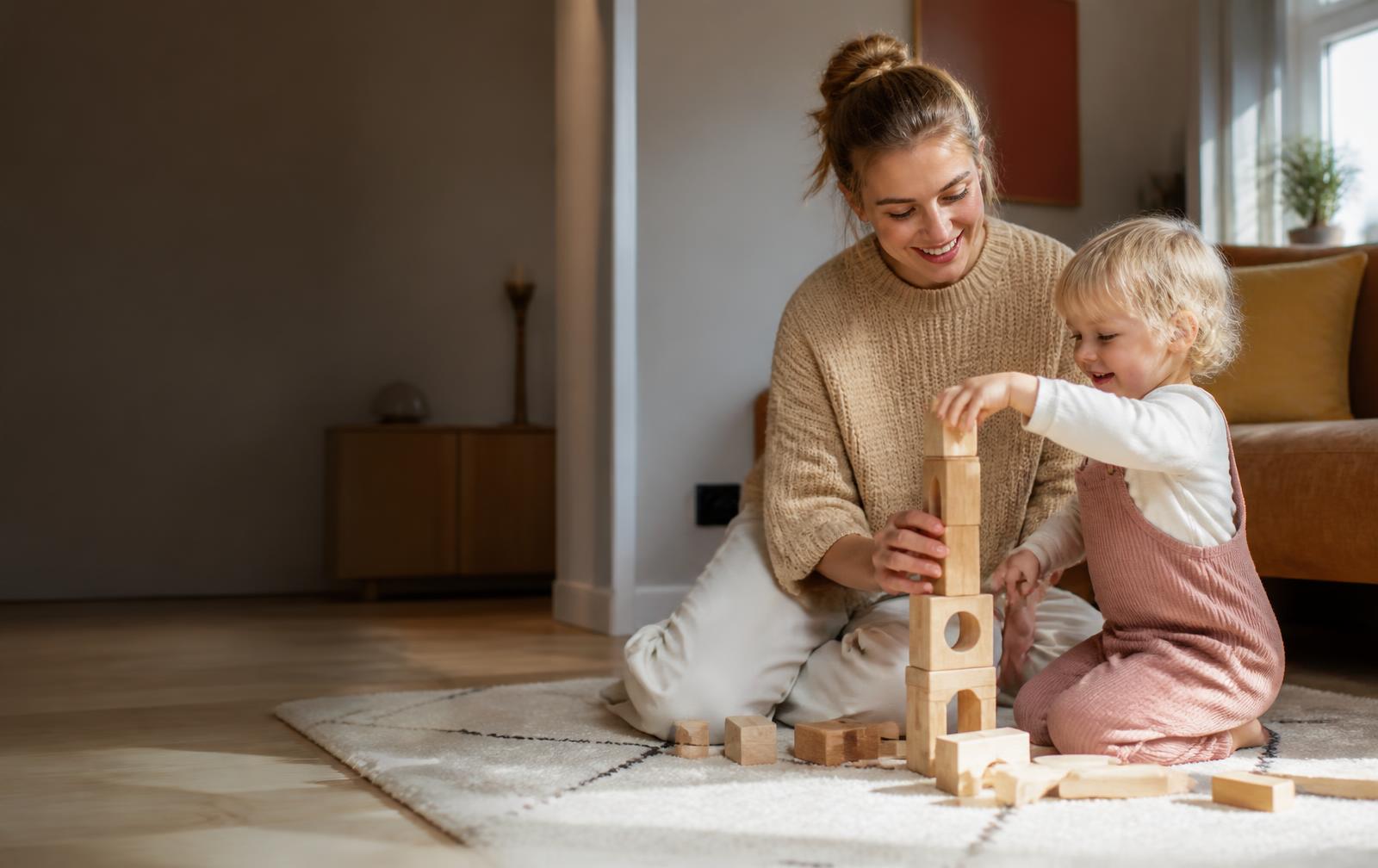 Børnepasser leger med to glade børn i en dansk stue — babysitter og barnepige i Danmark